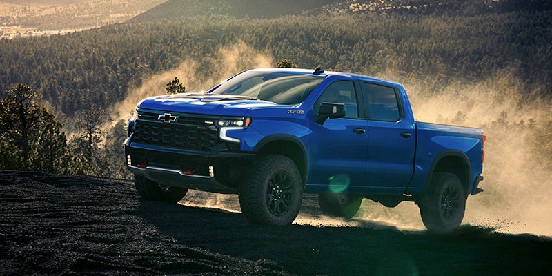 A Chevrolet Silverado 1500 driving on the road, showcasing its off-road capabilities and sturdy design.