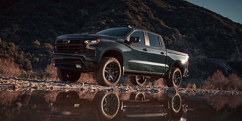 A Chevrolet Silverado 1500 driving on the road, showcasing its off-road capabilities and sturdy design.
