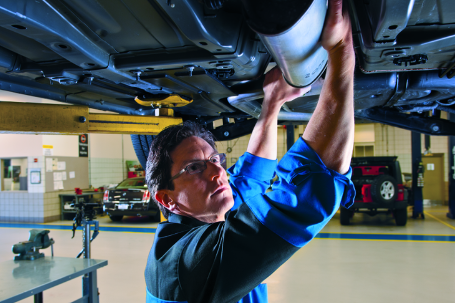Technician inspecting the bottom of a vehicle